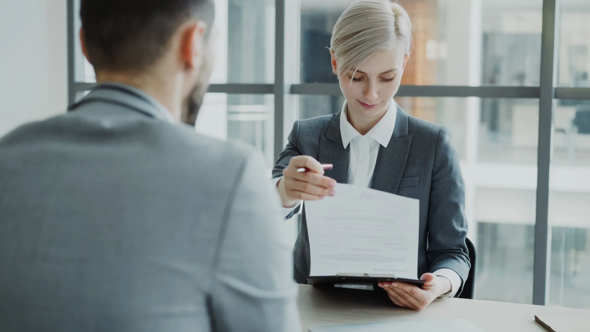 Duas pessoas em reunião de trabalho revisando um documento em um escritório